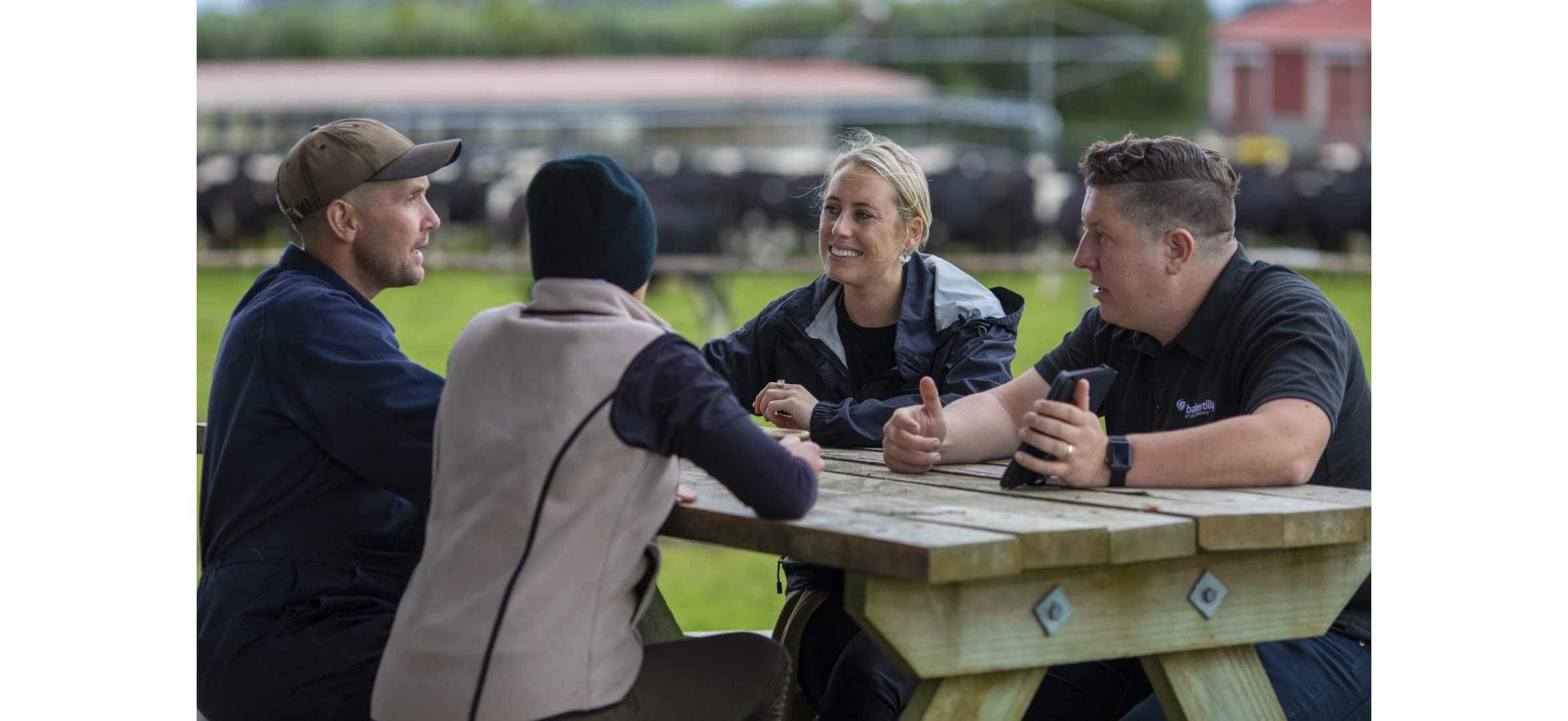 Donovan and Sophie sit at an outdoor table with two accountants talking.